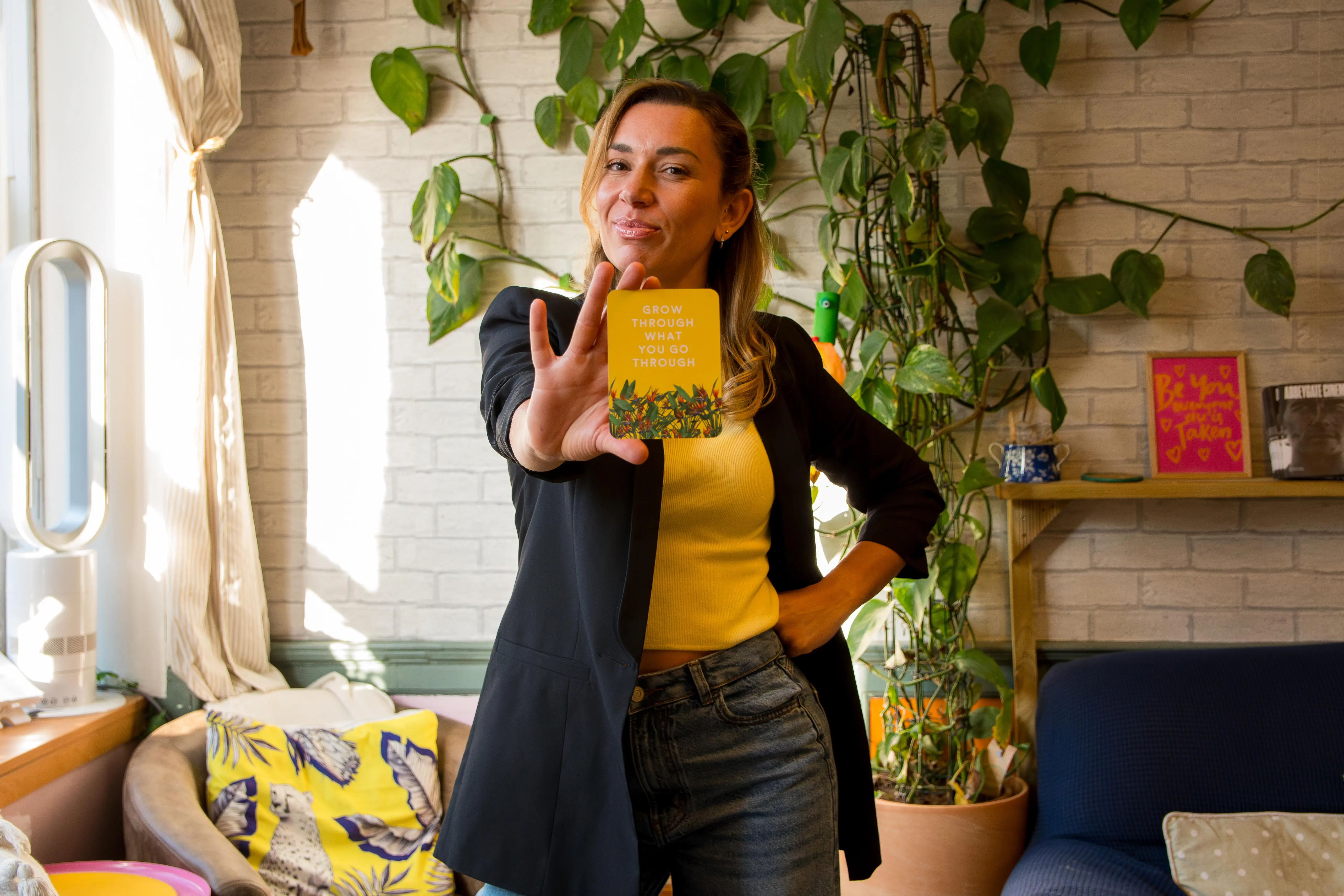 A female coach posing and holding a quote card that says grow through what you go through